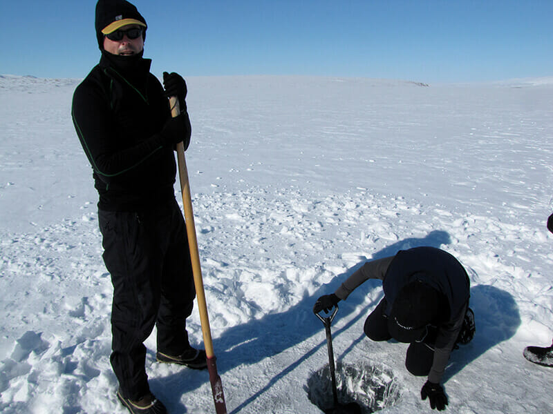 chopping a hole in the lake on a dog sledding trip in Arctic Alaska