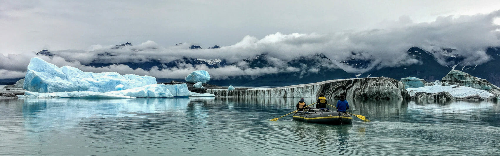 Guide rows a raft near icebergs on Alsek Lake in Glacier Bay National Park